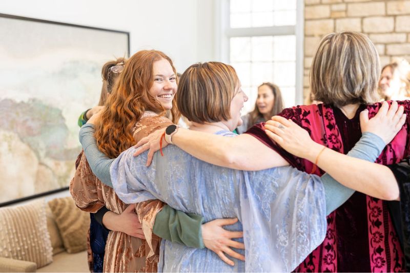 women standing in circle with arms around each other